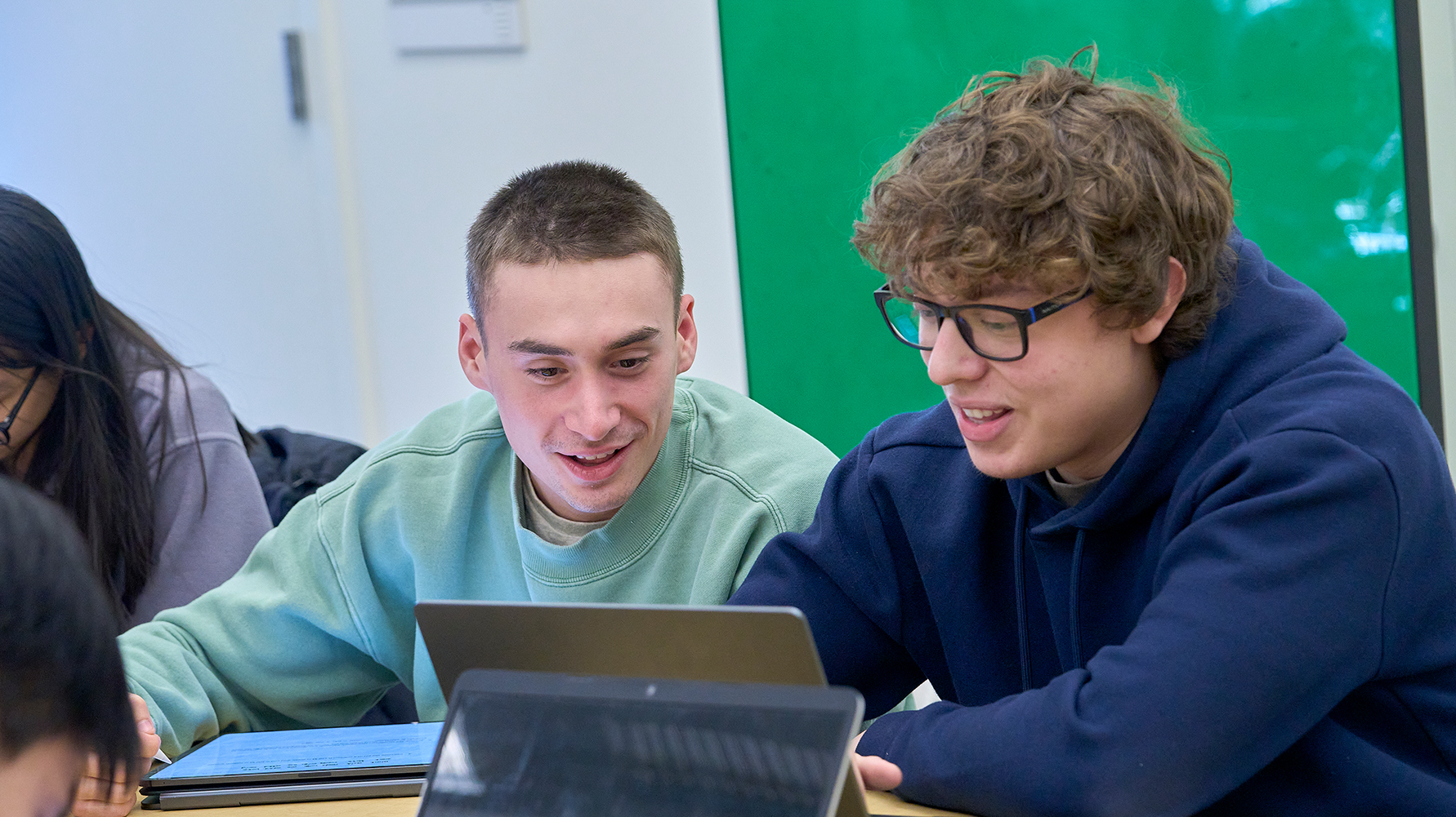 Two students collaborating on laptops in a classroom