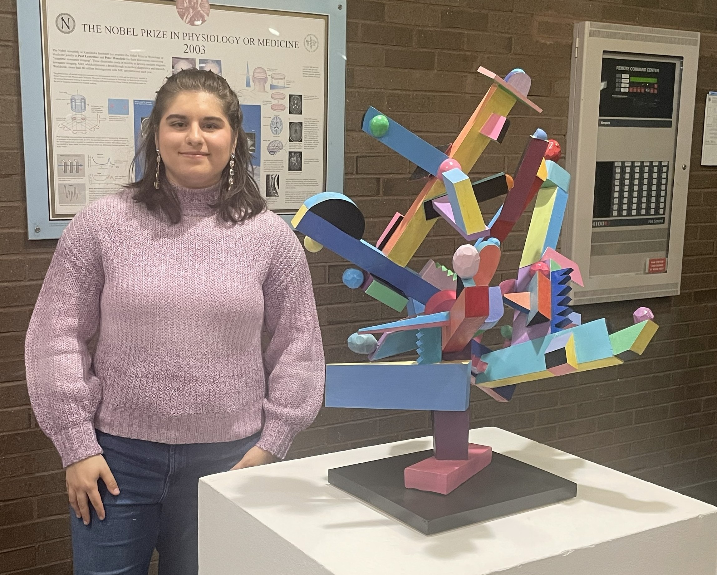 Female student at Stonybrook Brook University poses next to colorful art sculpture